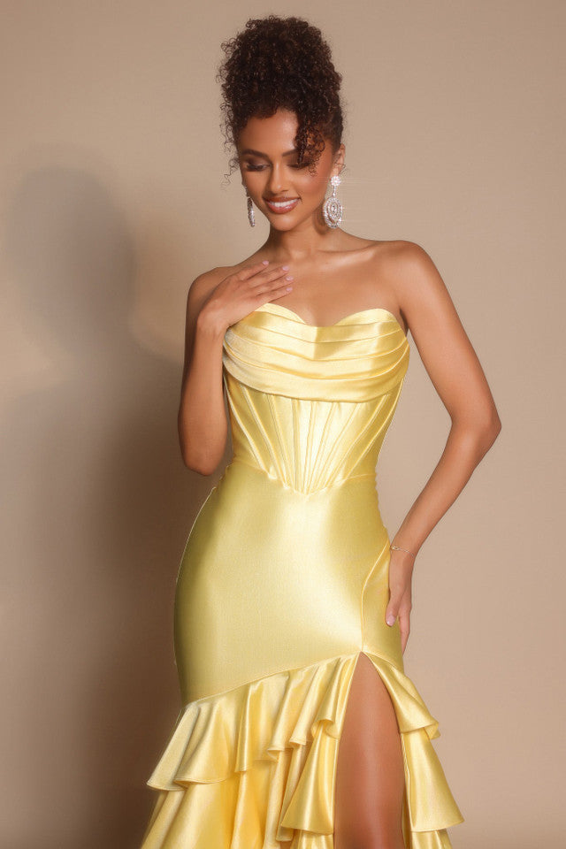 Woman wearing a yellow strapless dress with ruffled skirt against a beige background