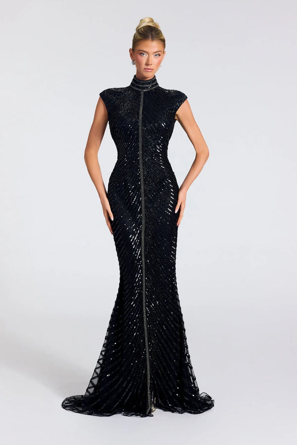 A model wearing a floor-length black sequined gown with a high mock neck, cap sleeves, and a front zipper, photographed against a light gray studio background.