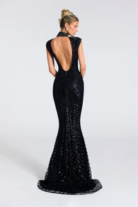 A woman modeling a black floor-length evening gown from the back, featuring a deep open back, cap sleeves, and dense beaded vertical detailing that creates a shimmering effect, set against a plain light gray studio background.