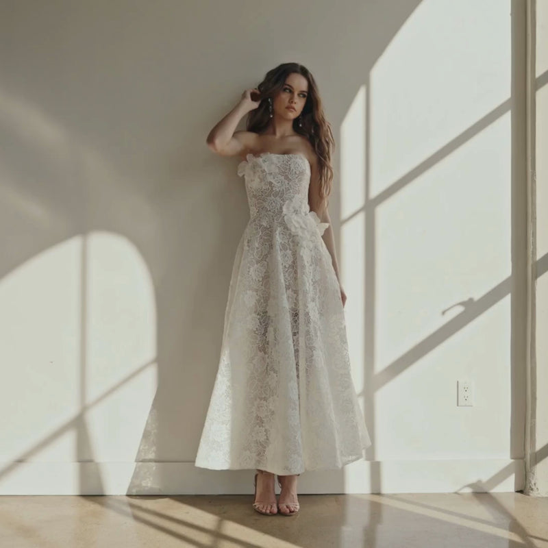 Model wearing the Helsi Sophie DR6474 strapless dress featuring 3D floral appliqués and a high-low silhouette.