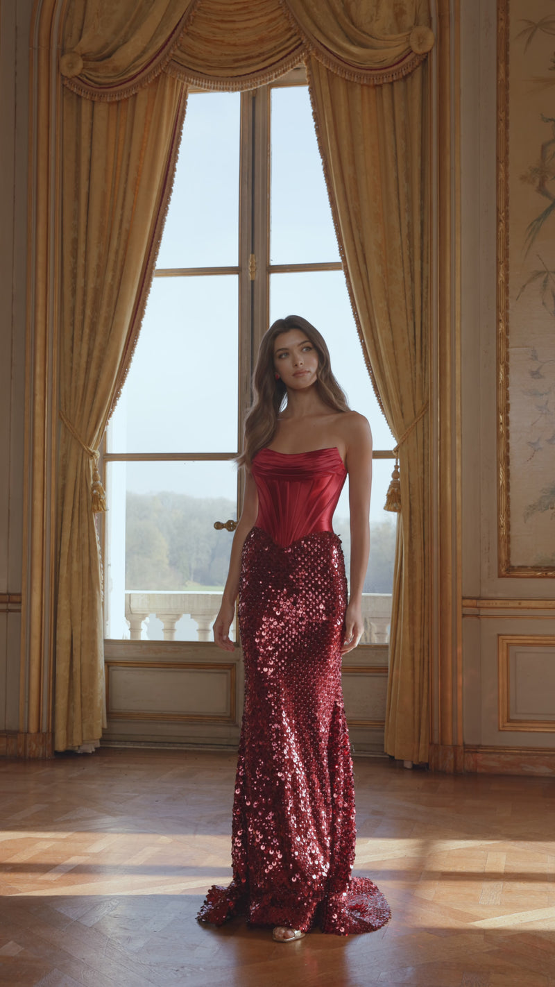 Model wearing Sherri Hill 58311 strapless corset gown with a sequin skirt and lace-up back.  This is a video of the model wearing the dress in the color wine.