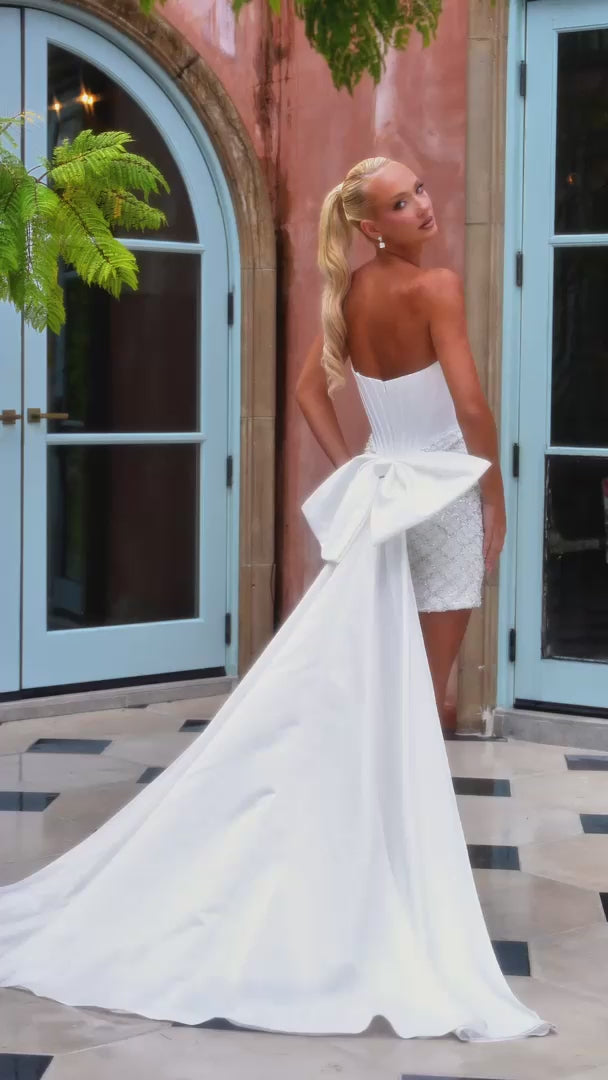 Video of Model wearing Portia & Scarlett PS26703 featuring a folded straight neckline, embellished mini skirt, oversized bow detail, open back, and detachable train.
