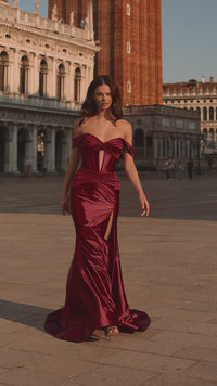 Model wearing Sherri Hill 57253 off-shoulder corset gown with lace-up back, ruched detailing, and high slit, styled for a red-carpet evening.