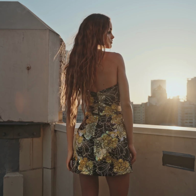 Model wearing the Helsi Brady DR6488 strapless mini dress featuring sequin floral appliqués and a flared silhouette. This is a video.