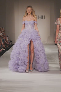 Shop the stunning Sherri Hill 55438 lilac shimmer tulle ballgown at Madeline's. Perfect for a glamorous evening, this long ballgown features an off-the-shoulder style, corset bodice, high slit, and ruffle skirt. Make a statement at your next special occasion in this elegant dress.  Video of Sherri Hill model wearing style 55438 walking down the runway at the fashion show.