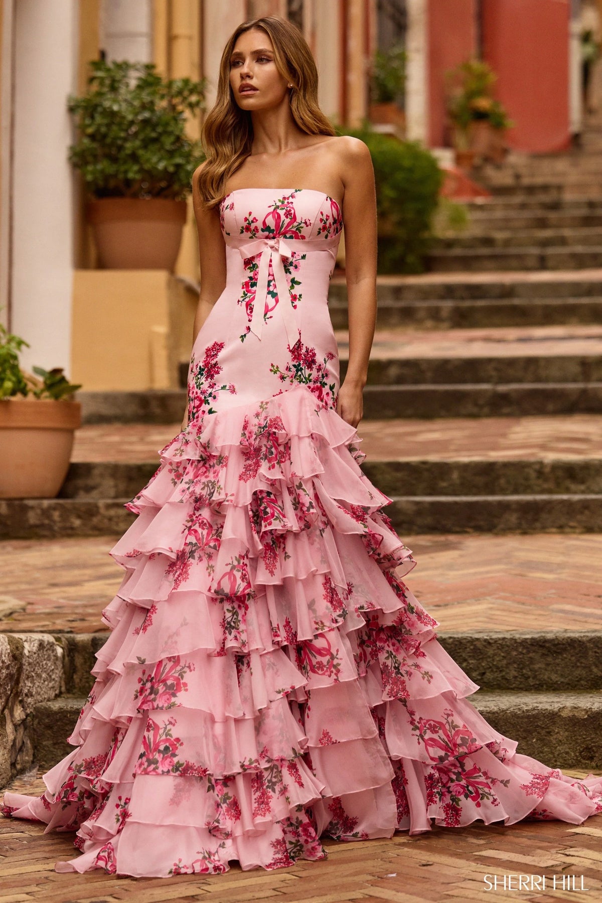 Model wearing Sherri Hill 57144 strapless gown with a fitted bodice and cascading ruffled tiered skirt.