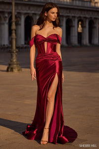 Woman wearing a burgundy evening gown with a high slit in an outdoor setting.