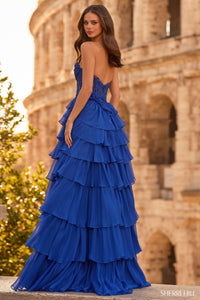 Woman in a blue evening gown with ruffled layers standing in front of the Colosseum.