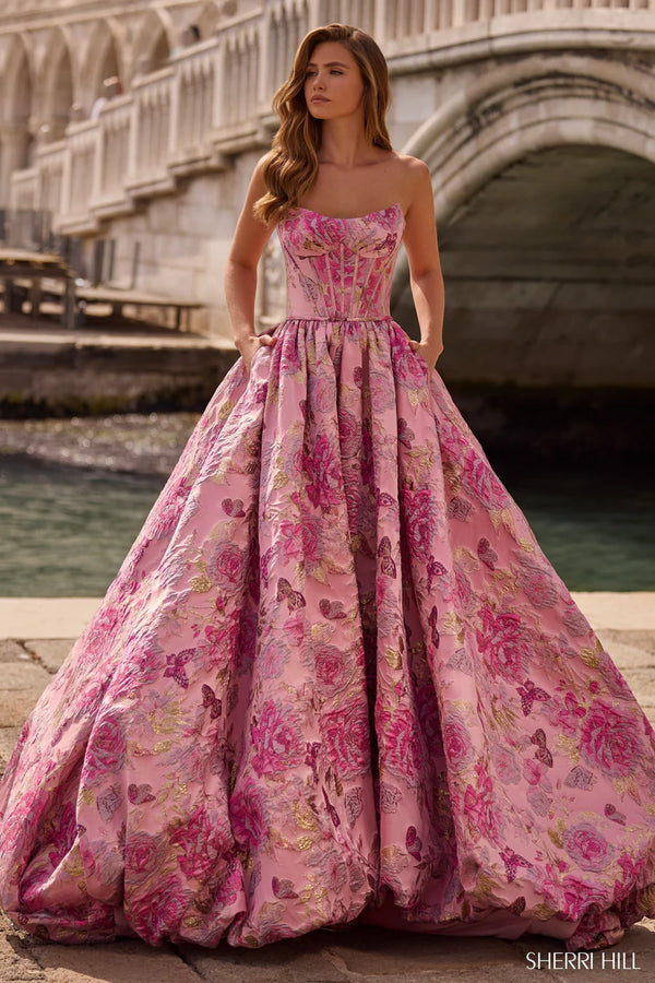 Woman in a pink floral gown standing by a bridge in an urban setting
