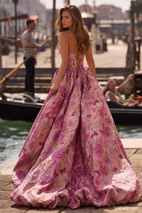 Woman in a pink floral dress standing by a waterfront with gondolas in the background
