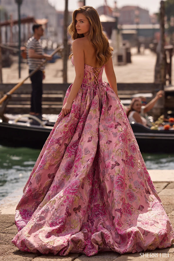 Woman in a pink floral dress standing by a waterfront with gondolas in the background