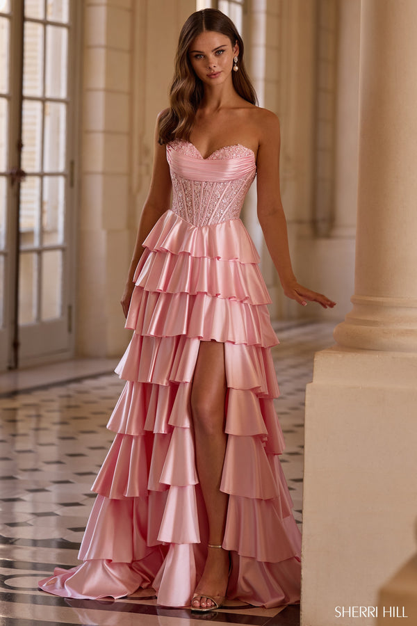 Model wearing Sherri Hill 57556 strapless gown with corset bodice, tiered ruffle skirt, high slit, and lace-up back.