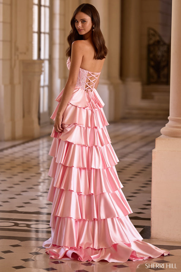 Model wearing Sherri Hill 57556 strapless gown with corset bodice, tiered ruffle skirt, high slit, and lace-up back.
