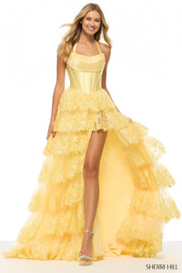Woman wearing a yellow Sherri Hill dress with ruffled layers on a white background