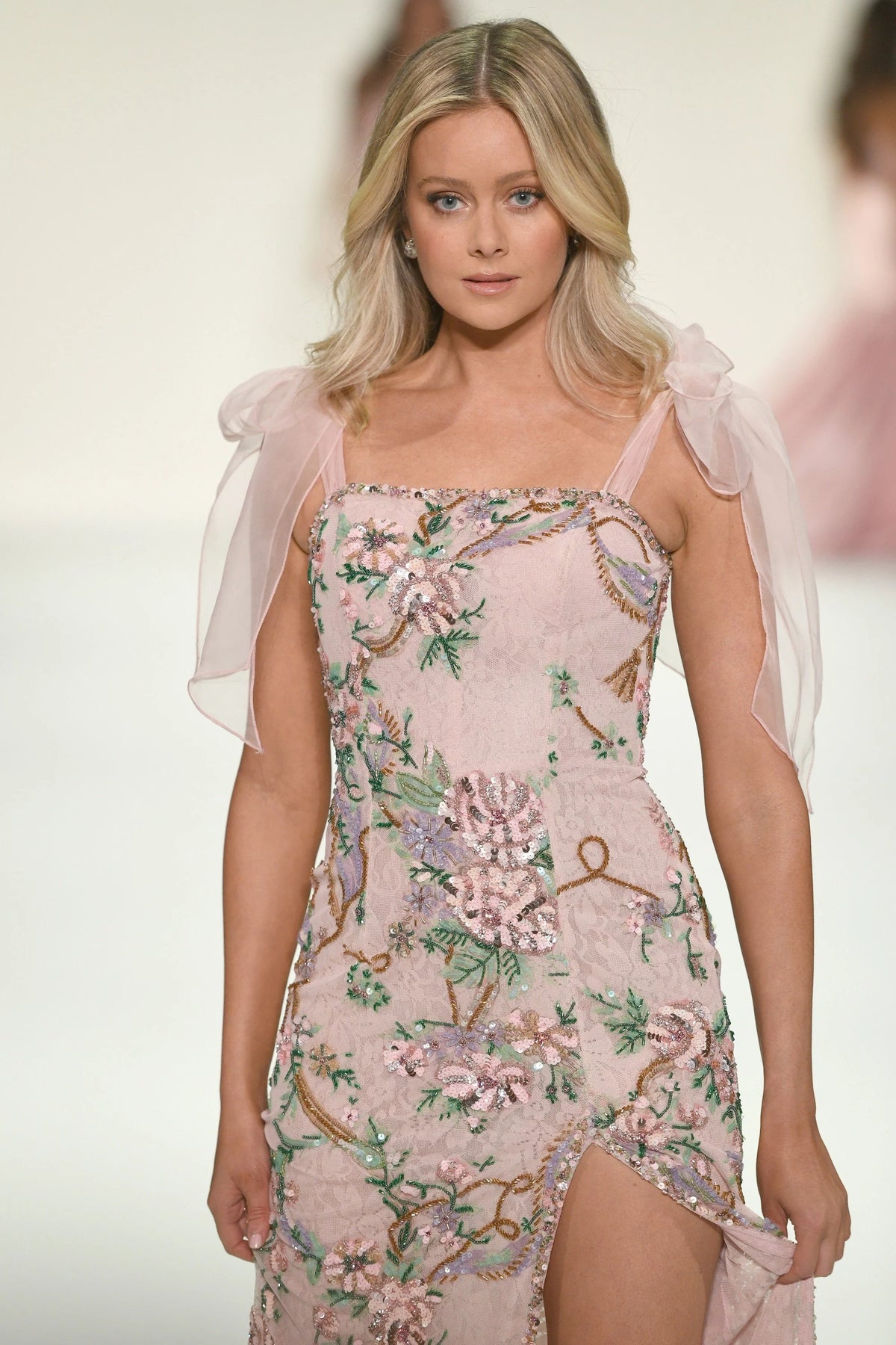 Model wearing Sherri Hill 57602 fitted gown with beaded floral detailing, shoulder bows, and skirt slit.