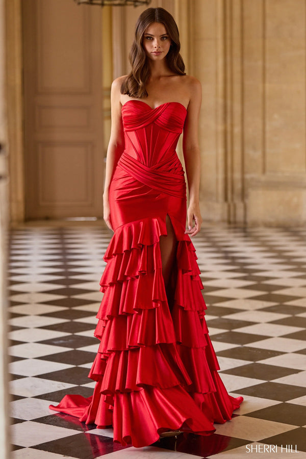 Woman wearing a red strapless gown with ruffled layers on a checkered floor.