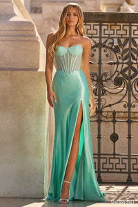 Woman wearing a turquoise evening gown with a high slit in front of an architectural background.