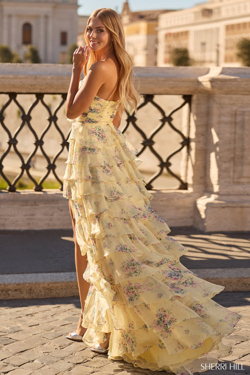 Model wearing the Sherri Hill 57907 strapless evening gown featuring a fitted bodice, ruffle skirt, and high slit at a formal outdoor location.