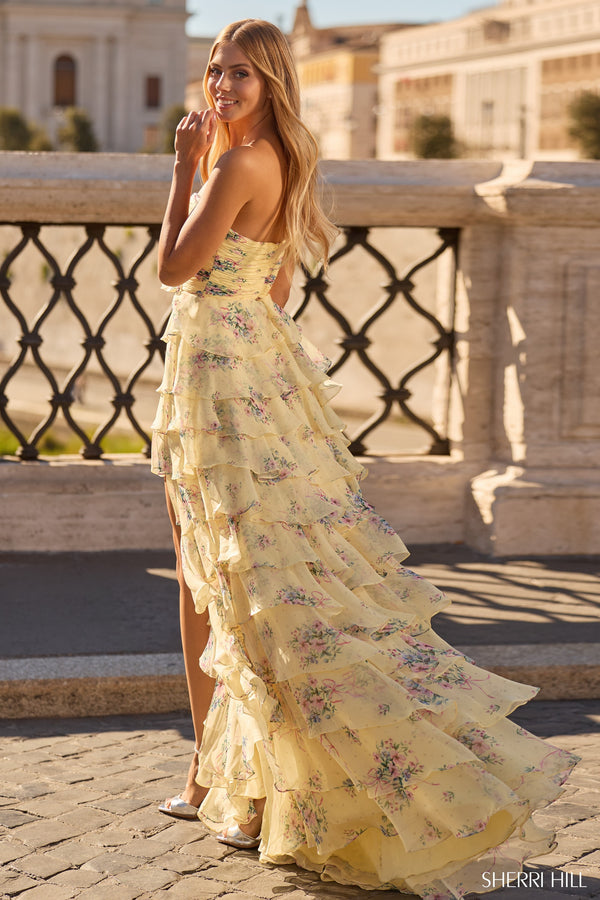 Model wearing the Sherri Hill 57907 strapless evening gown featuring a fitted bodice, ruffle skirt, and high slit at a formal outdoor location.