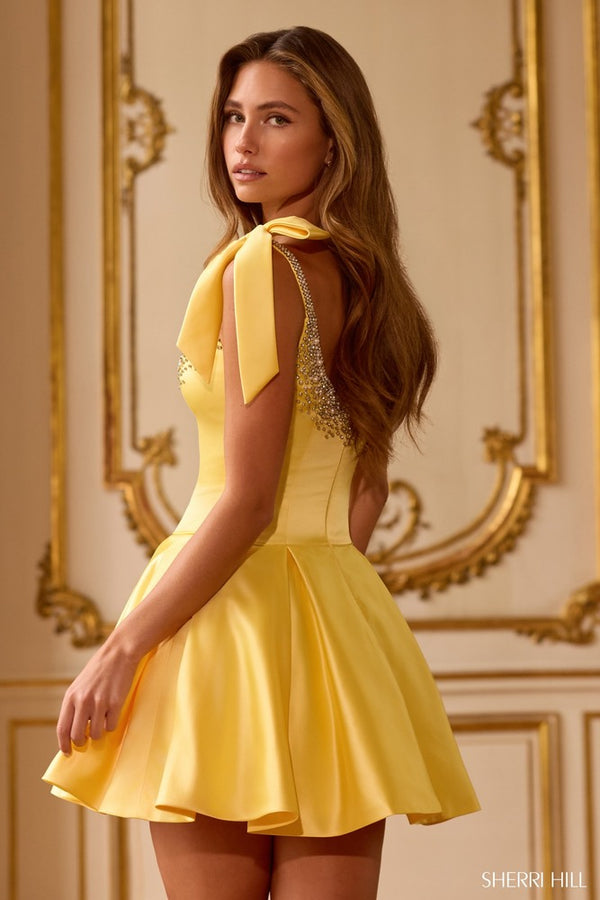 Woman wearing a yellow dress with a decorative neckline in an elegant interior setting.