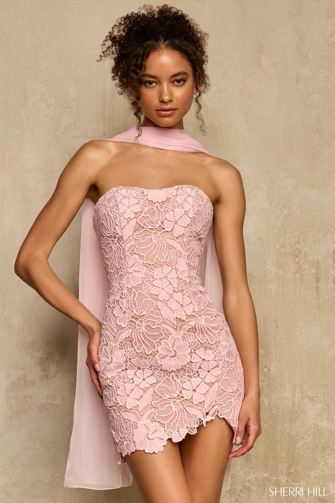 Woman wearing a pink lace dress with a matching cape against a beige background