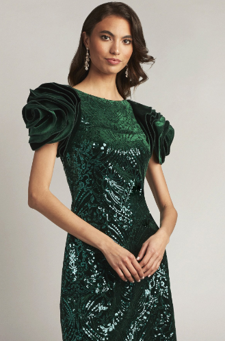 A woman wearing a close-fitting velvet sheath dress with oversized rosette sleeves and intricate paillette embroidery, perfect for elegant evening occasions.