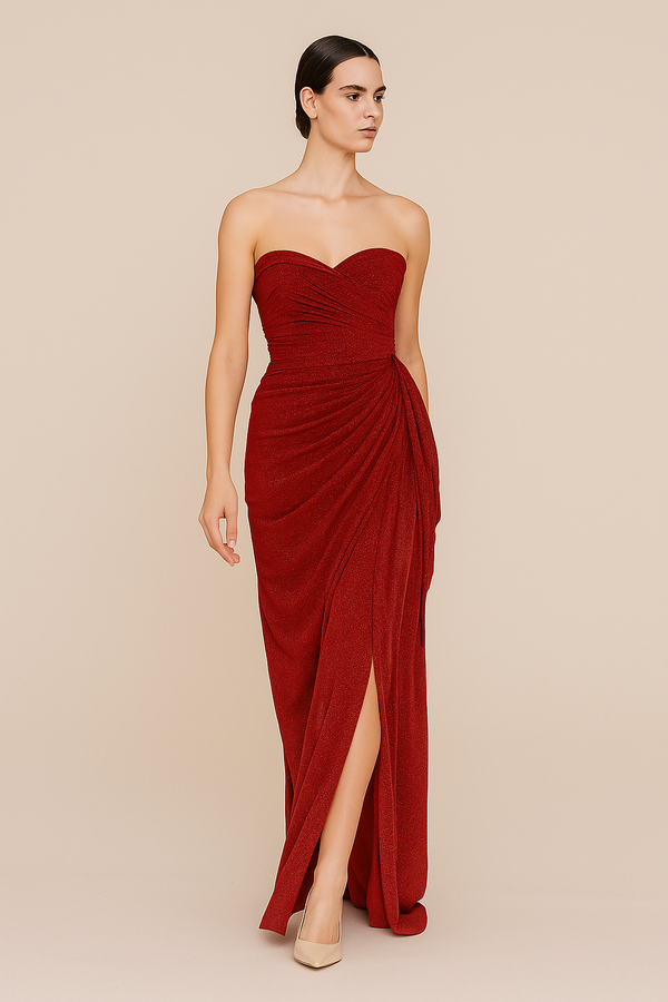 Woman wearing a strapless red gown with a slit on a beige background