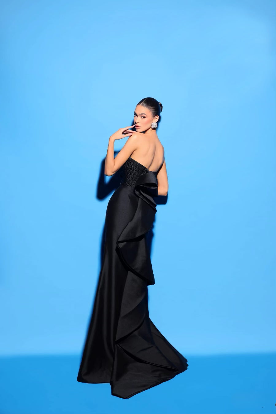 Tarik Ediz 98441 Elegant Strapless Sheath Evening Dress - A timeless strapless evening dress with a straight neckline, sheath silhouette, front slit, and a modern back ruffle detail. Make a statement with elegance and contemporary flair.  The model is wearing the dress in the color black.  This is a view of the back of the dress.