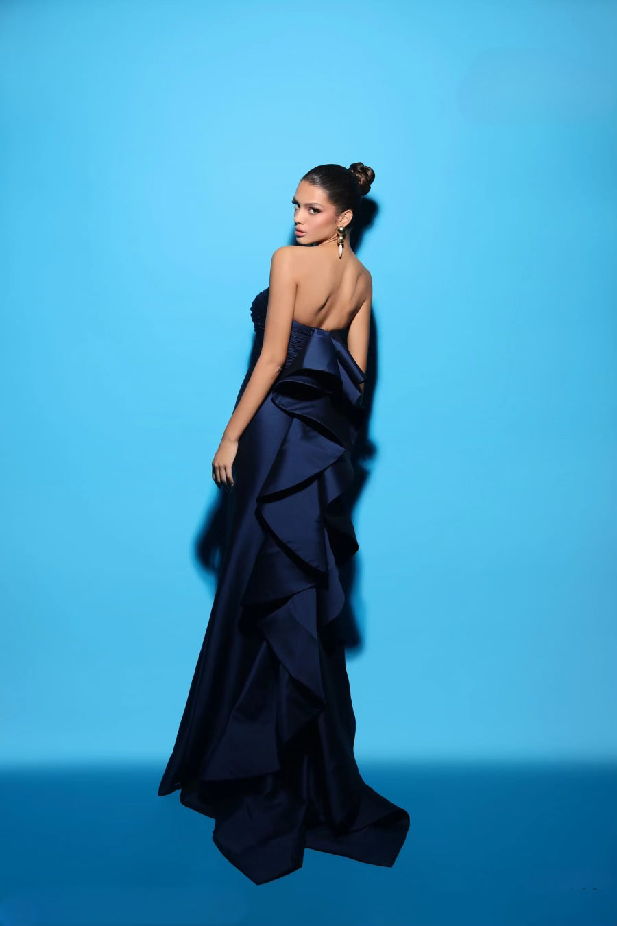 Tarik Ediz 98441 Elegant Strapless Sheath Evening Dress - A timeless strapless evening dress with a straight neckline, sheath silhouette, front slit, and a modern back ruffle detail. Make a statement with elegance and contemporary flair.  The model is wearing the dress in the color royal blue.  This is a view of the back of the dress..