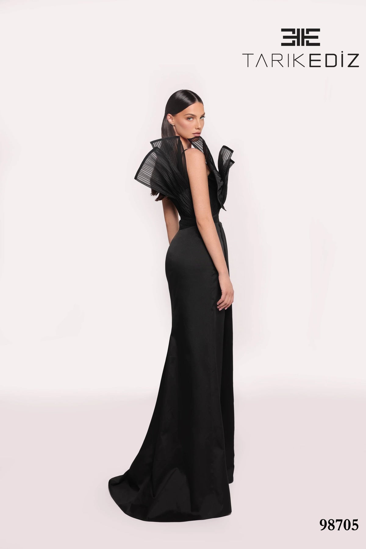 Black evening gown with sheer sleeves on a white background, featuring the brand 'TARIKE DIZ'.