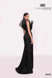 Black evening gown with sheer sleeves on a white background, featuring the brand 'TARIKE DIZ'.