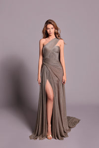 Model wearing Tarik Ediz 99041 one-shoulder draped gown with high slit and flowing back panel.
