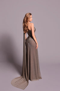 Model wearing Tarik Ediz 99041 one-shoulder draped gown with high slit and flowing back panel.