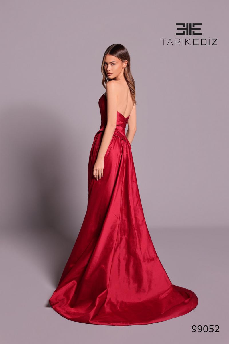 Red evening gown on a model with 'Tarik Ediz' branding on a gray background