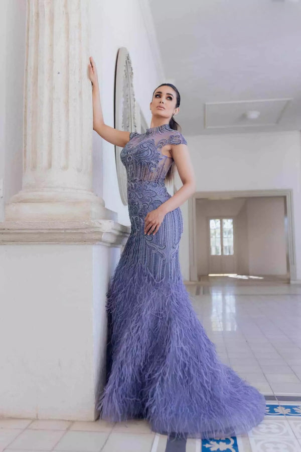 Turn heads in Terani Couture's feathered mermaid dress, featuring a high neck and intricate bead embellishments. Perfect for special evening events. Available at Madeline's Boutique in Toronto and Boca Raton, Florida.