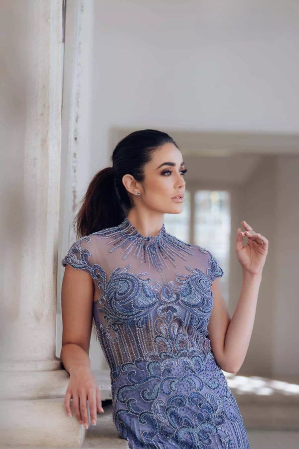 Turn heads in Terani Couture's feathered mermaid dress, featuring a high neck and intricate bead embellishments. Perfect for special evening events. Available at Madeline's Boutique in Toronto and Boca Raton, Florida.
