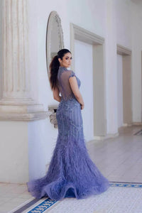 Turn heads in Terani Couture's feathered mermaid dress, featuring a high neck and intricate bead embellishments. Perfect for special evening events. Available at Madeline's Boutique in Toronto and Boca Raton, Florida.