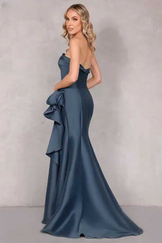 A stunning Mikado evening dress by Terani with an off-shoulder neckline, open back, and a draped bow feature on the waist. Perfect for evening events and as a mother-of-the-bride or mother-of-the-groom dress.