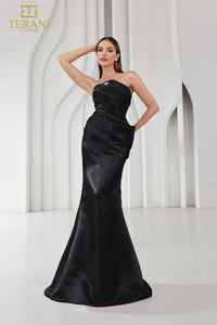 Model wearing Terani Couture 251E4231 one-shoulder gown with ruffle detail and floor-length silhouette