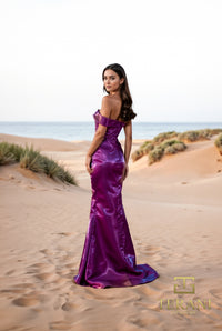 Model wearing Terani 252E5162 off-shoulder gown with draped bodice, rosette detail at hip, and fit-and-flare silhouette.  Model is wearing the color plum.  This is a back view of the dress.