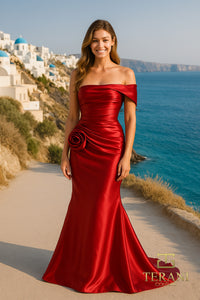Model wearing Terani 252E5162 off-shoulder gown with draped bodice, rosette detail at hip, and fit-and-flare silhouette.  Model is wearing the color wine.