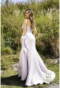 Model wearing Terani 252E5200 strapless metallic jacquard fit and flare gown with side draping detail.  Model is wearing rose pink.  Back View.