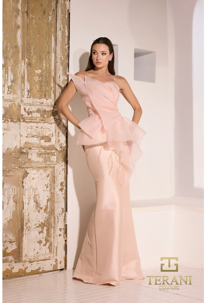 Model wearing Terani Couture 252E5550 strapless gown with peplum detail and mermaid silhouette on the beach.  Model is wearing the dress in the color blush.