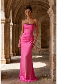 Woman in a pink strapless gown standing in an archway with stone walls.