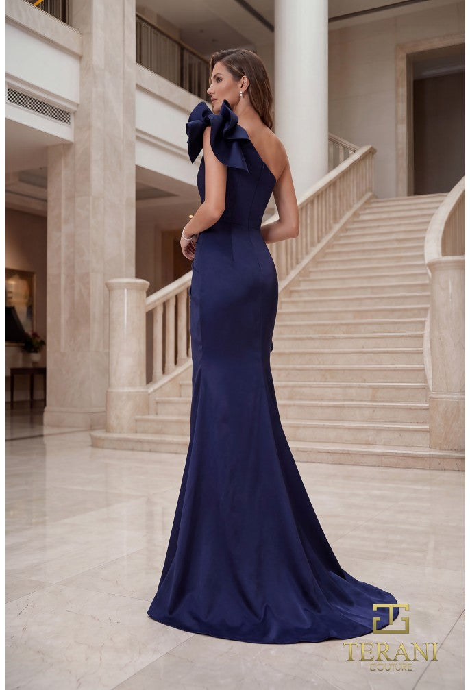Model wearing Terani 262E7132 one-shoulder mermaid gown in the color navy with draped bodice, statement bow accents, fitted silhouette, and sweep train.