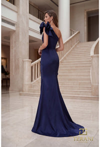 Model wearing Terani 262E7132 one-shoulder mermaid gown in the color navy with draped bodice, statement bow accents, fitted silhouette, and sweep train.