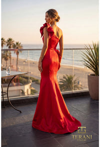 Model wearing Terani 262E7132 one-shoulder mermaid gown in the color red with draped bodice, statement bow accents, fitted silhouette, and sweep train.