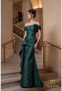 Woman in a evergreen evening gown standing on a staircase with 'Terani' branding.