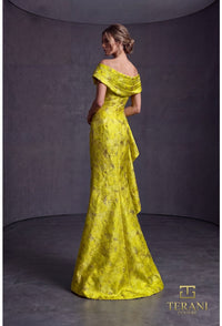 Woman wearing a lemon yellow evening gown with floral details against a gray background, Terani Couture branding visible.