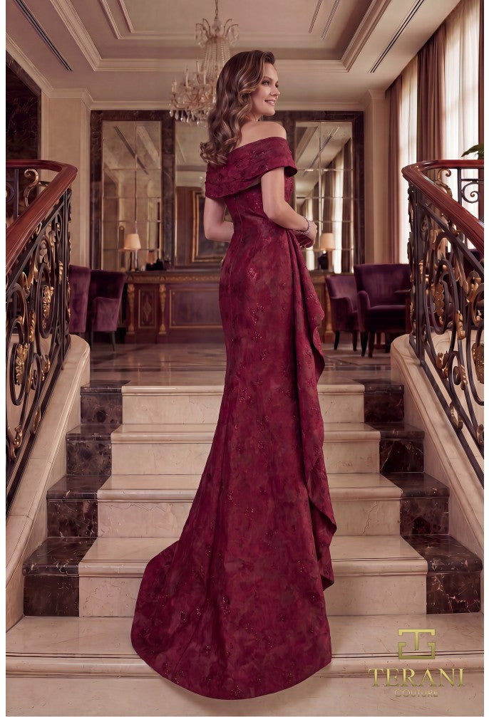 Woman in a merlot color evening gown standing on a staircase in an elegant interior setting.